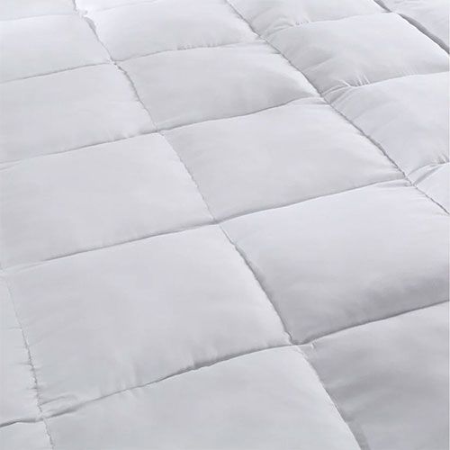 A person is gently touching the top of a mattress, assessing its softness and comfort.