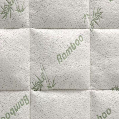 A woman in pink pajamas reclines on a mattress, appearing relaxed and comfortable.